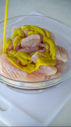 a glass bowl filled with meat and sauce on top of a white countertop next to a yellow straw