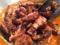 some meat is being cooked in a bowl with sauce and a spatula on the side