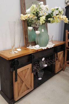 a table with flowers and vases on it in front of a mirror, next to a chair