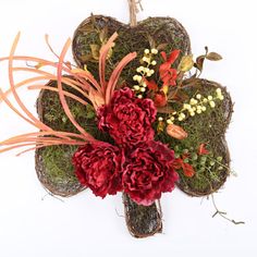 a bouquet of red flowers and greenery in the shape of a heart on a white background