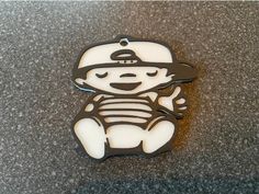 a white and black brooch sitting on top of a gray counter next to a bottle opener