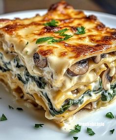 a white plate topped with lasagna covered in mushrooms and spinach garnished with parsley