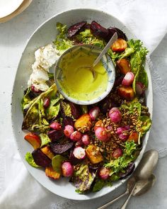 a bowl filled with salad and dressing on top of a white table cloth next to utensils