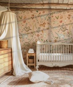 a baby's room with a white crib, dresser and wallpapered walls