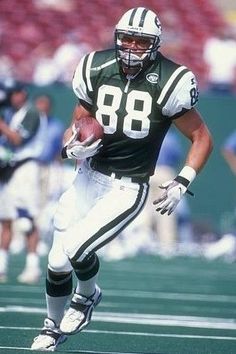 a football player running with the ball in his hand and people watching from the stands behind him