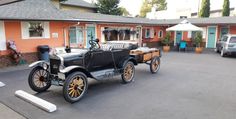 an old fashioned car parked in front of a motel room with orange walls and white trim