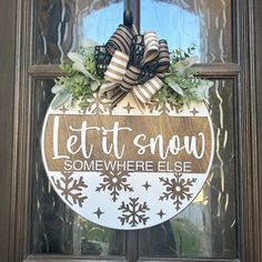 a wooden sign that says let it snow somewhere else on the front door and window