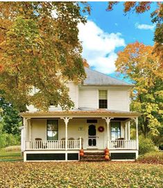 a white house surrounded by trees and leaves