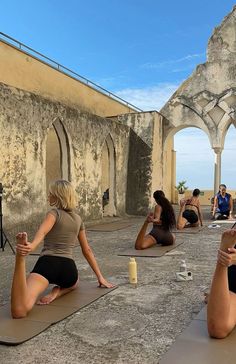 several women are sitting on yoga mats in front of an old building