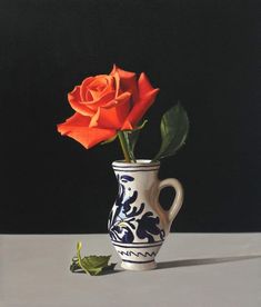 a single orange rose in a white and blue vase