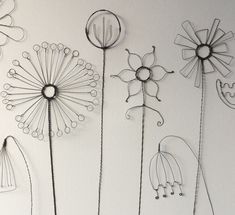 four metal dandelions are hanging on the wall