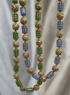 Enhance your collection with these two Caged Bead Necklaces. One features green beads, and the other showcases blue beads. Both necklaces are complemented by gold foil nakshi balls. The unique caged design adds texture and elegance, making it a versatile piece for both casual and formal occasions. Perfect for those who appreciate detailed craftsmanship and a touch of color in their jewelry collection. Material : 24Kt Gold foil, Lac Stones: Semi precious blue beads, semi precious green beads, gol Nakshi Balls, Bead Necklaces, Gemstone Beaded Necklace, Green Beads, Tourmaline Necklace, Pin Pendant, 24kt Gold, Pendant Rings, Green Bead