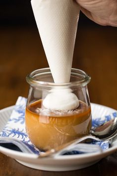 someone is dipping something into a small glass jar with ice cream on top and spoons