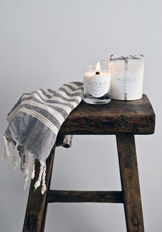 two candles are sitting on a stool next to a striped towel and wrapped gift box