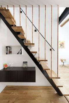 a man is walking up the stairs in a house with wood flooring and white walls