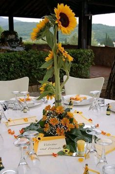 a sunflower centerpiece on a table with place settings