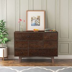 a wooden dresser sitting next to a potted plant on top of a hard wood floor