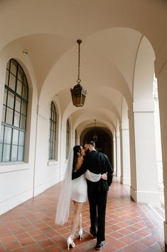 a bride and groom kissing in an archway