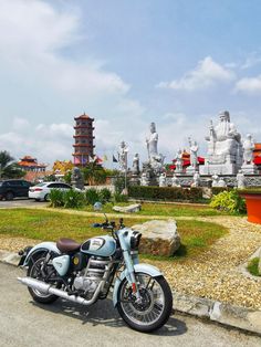 a blue motorcycle parked in front of a pagoda and other statues on the side of a road