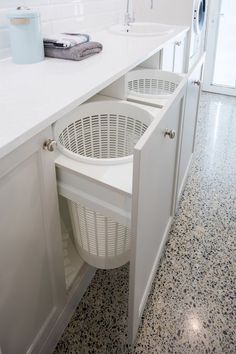 a laundry basket is in the middle of an open cabinet