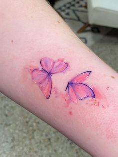 a small tattoo on the arm of a woman with pink butterflies painted on it's side