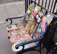 a bench made out of skateboards sitting on the side of a street next to a fence