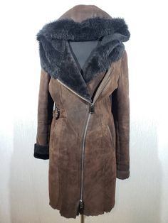 Wonderful women's warm sheepskin coat with genuine fur. Stylish long brown sheepskin coat with metal zipper and hood. The sheepskin coat is made of beautiful, warm sheep fur. The outer side of the sheepskin coat has a decorative coating in the form of a velvet surface, which changes shade when you run your hand over it. The sheepskin coat fastens with a metal zipper with a double fastener sewn on top, slightly to the left of the center of the sheepskin coat. The leather jacket has two convenient front pockets. The sheepskin cuffs can be turned up to embellish or shorten the sleeves. A distinctive feature of a sheepskin coat is a hood to protect against the cold. Such a sheepskin coat will warm you in cold late autumn and harsh winter. A stylish, warm and pleasant to wear sheepskin coat wil Hooded Brown Sheepskin Fur Coat, Luxury Hooded Sheepskin Fur Coat, Women Leather Vest, Harsh Winter, Late Autumn, Sheepskin Coat, Womens Jackets, Leather Vest, Metal Zipper