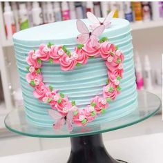 there is a cake decorated with flowers and butterflies on the top of it, in the shape of a heart