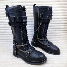 Bolt-415 By Demonia Vegan Leather 1 1/4" Heel Size: Men's 1.25" (32mm) Heel 18 Eyelet Unisex Knee High Combat Boot Featuring Featuring Studded Buckled Top Panel, Harness Strap, O-Ring, D-Ring , Hanging Chain Details And Branded Metal Plate @ Toe, Inside Zip Closure. Mens Goth Boots, Silver Punk Boots For Streetwear, Silver Boots With Rivets And Round Toe, Silver Round Toe Boots With Rivets, Silver Gothic Boots With Metal Feet, Gothic Silver Boots With Metal Feet, Silver Leather Moto Boots With Round Toe, Gothic Silver Boots With Round Toe, Emo Fashion Men