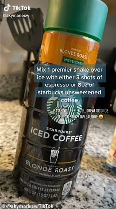 a starbucks coffee cup sitting on top of a counter next to a blender bottle