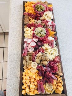 an assortment of meats and cheeses laid out on a long wooden platter