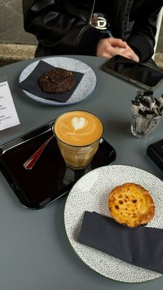 a table topped with plates filled with desserts and drinks next to a laptop computer