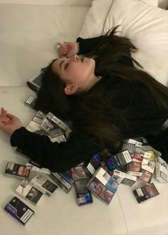 a woman laying on top of a bed with lots of cards all over her body