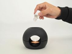 a person is lighting a small candle in a black holder