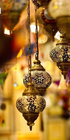 three hanging lamps with blue and white designs on them in a room filled with other items