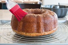 a bundt cake on a cooling rack with a red brush sticking out of it