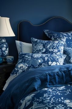 a bed with blue and white comforters in a bedroom next to a night stand