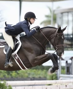 a woman riding on the back of a brown horse jumping over an obstacle with her legs in the air