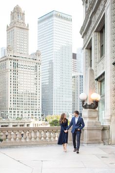 a man and woman walking in front of tall buildings