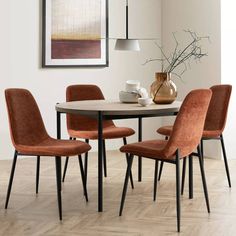 a dining room table with four chairs and a vase on the wall in front of it