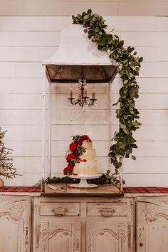 a wedding cake sitting on top of a wooden dresser next to a christmas tree and fireplace