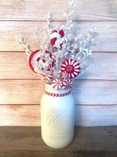 a mason jar filled with candy canes and snowflakes on top of a wooden table