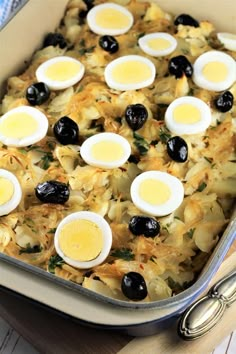 a casserole dish with eggs, cheese and olives