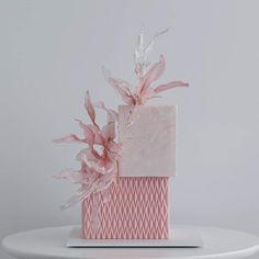 a pink gift box with flowers on it sitting on top of a white table next to a gray wall