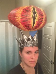 a woman wearing a helmet with spikes on her head and an eyeball above her head