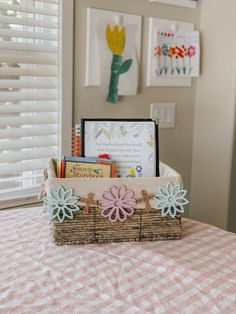 a basket filled with books sitting on top of a pink and white checkered table cloth