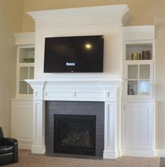 a flat screen tv mounted on the wall above a fireplace in a living room with built - in bookcases