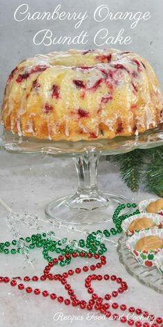 an orange bundt cake with cranberry sauce on top and christmas decorations around it