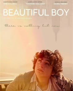 a man sitting on top of a wooden bench next to a poster that says beautiful boy