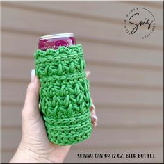 a hand holding a can holder made out of crocheted yarn with a soda in it